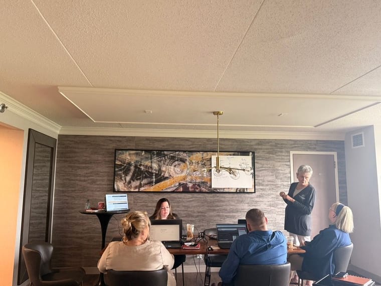 Members of the Contractor In Charge team working on laptops in a meeting room